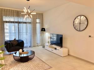 a living room with a tv and a clock on the wall at White Sage - Tranquil Haven 1BR With Burj Views in Dubai
