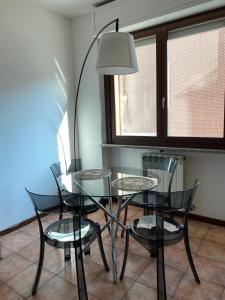 uma sala de jantar com uma mesa de vidro e cadeiras em Appartamento ONE em Novara