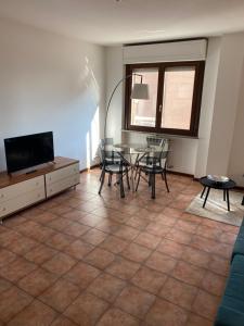 sala de estar con mesa, sillas y TV en Appartamento ONE, en Novara