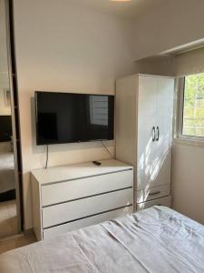 um quarto com uma televisão e uma cómoda com uma cama em Único 2 ambientes, terraza y parrilla en Núñez em Buenos Aires
