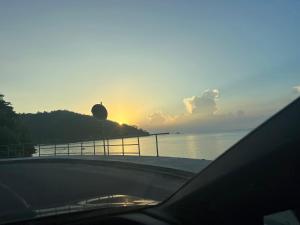 una puesta de sol sobre un cuerpo de agua con un coche en Kanasuk Self catering Apartments, en Baie Lazare Mahé
