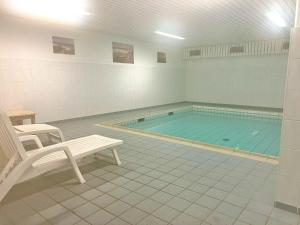 a swimming pool with a chair and a bench in a room at Robbe in Westerland