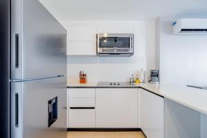 uma cozinha com armários brancos e um frigorífico de aço inoxidável em San Francisco by Wynwood House em Cidade do Panamá