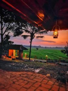 Vistas a una casa con una palmera y una puesta de sol en Happy Land en Shoranūr