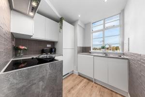 a kitchen with white cabinets and a sink at Central London Luxury, Relaxing Apartment! 2 Mins from Paddington Station! in London