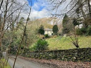 a stone wall next to a road and a house at Panteinion Hall in Llanbedr