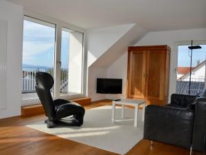 a living room with a black chair and a television at Ferienwohnung 180 Grad in Wasserburg am Bodensee