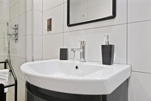 a white sink in a bathroom with white tiles at Stunning 2 Bed basement flat in Hammersmith in London