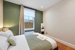 a bedroom with a large bed and a window at Stunning 2 Bed basement flat in Hammersmith in London