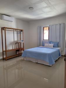 Un dormitorio con una cama azul y una ventana en Casa Akua, en São Miguel dos Milagres