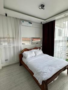 um quarto com uma cama com lençóis brancos e uma janela em Prayer Mountain Cove em Kampala
