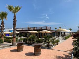 a resort with tables and umbrellas and palm trees at Little Venice in Sottomarina