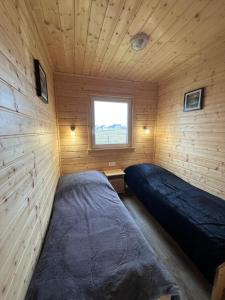 a bedroom with two beds in a wooden room at Domki letniskowe Gąski in Gąski