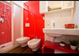 La salle de bains rouge est pourvue de toilettes et d'un lavabo. dans l'établissement Home Sweet Home, à Alghero