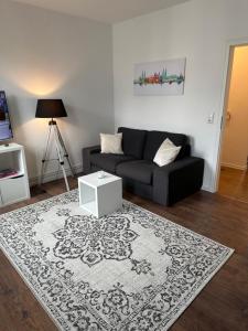 a living room with a black couch and a white rug at Ferienwohnung Hansetraum Lübeck in Lübeck