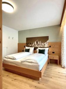 Schlafzimmer mit einem großen Bett mit einem Kopfteil aus Holz in der Unterkunft Hotel Jägerhof in Kolfuschg