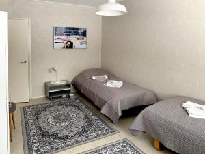 a room with two beds and a lamp and a rug at Apartment Ryti in Kokkola