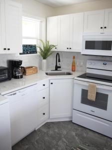 una cucina bianca con armadi bianchi e lavandino di 508 A The Shore Break Cottage a Virginia Beach