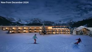 two people skiing in the snow in front of a hotel at Hotel Cendevaves in Santa Cristina Gherdëina