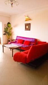 uma sala de estar com um sofá vermelho e uma mesa em Appartement à Asilah Marina Golf vue mer em Asilah