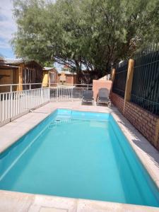 a blue swimming pool with two chairs and a fence at Brisas de montaña in Las Compuertas