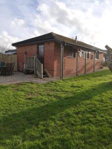 a brick house with a porch and a yard at The Lodge, countryside living in Churchdown