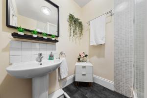 a white bathroom with a sink and a shower at Heart of London Luxury, 1 Min Walk from Paddington Station, Beautiful Apartment with Smart TV in London