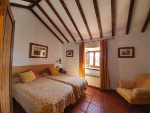 um quarto com uma cama, uma cadeira e uma janela em Molino de Las Pilas - Ecoturismo - Caminito del Rey em Teba