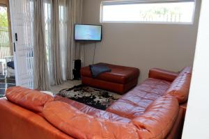a living room with a leather couch and a television at Cloud 9 : Where you can daydream in Kenton on Sea