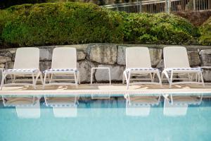 three lounge chairs sitting next to a swimming pool at Seehotel Urban in Bodensdorf