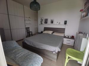 - une chambre avec deux lits et une chaise verte dans l'établissement Villetta Lunady vicino al mare, à Marina di Ragusa
