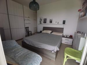 1 Schlafzimmer mit 2 Betten und einem grünen Stuhl in der Unterkunft Villetta Luxury Lunady vicino al mare in Marina di Ragusa