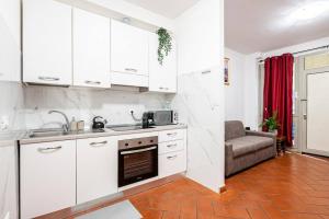 una cucina con armadi bianchi, lavandino e divano di [Firenze] New and Elegant Suite a Firenze