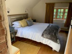 a bedroom with a large bed with white sheets and pillows at Beautiful converted Coach house for two in Hoptonheath