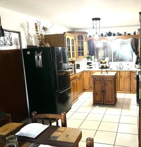 uma cozinha com um frigorífico preto e armários de madeira em Casa bella Loma encantada em San José del Cabo