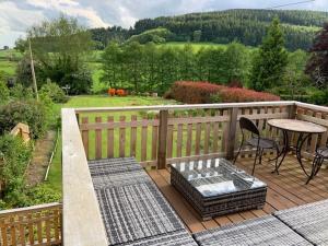 a wooden deck with a table and a table and chairs at Beautiful converted Coach house for two in Hoptonheath