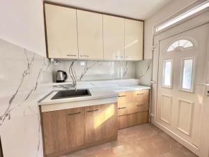 a kitchen with wooden cabinets and a sink and a door at Sunny balconies apartments Skadar Lake in Virpazar