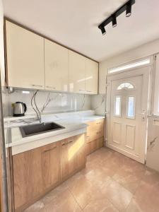 cocina con armarios blancos, fregadero y puerta en Sunny balconies apartments Skadar Lake en Virpazar
