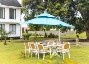 a table and chairs under a blue umbrella at BWAGAmoyo by Enamour in Yombo