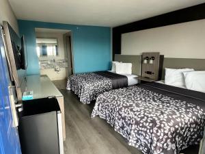 a hotel room with two beds and a television at Days Inn by Wyndham El Paso Airport East in El Paso