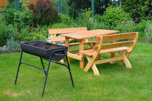 a barbecue grill next to a wooden table and bench at Pokoje u Danuty in Piwniczna-Zdroj