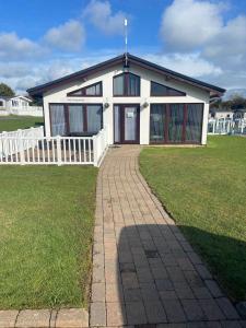 a white house with a white fence in front of it at Ger-Y-Bwlch - Spacious static on 5star site with Swimming Pool in Benllech