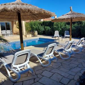 a row of chairs and umbrellas next to a pool at Casa La Rana in Calafat