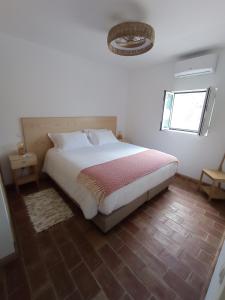 a bedroom with a large bed and a window at Casa do Livramento in Luz de Tavira