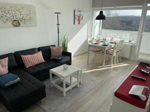 ein Wohnzimmer mit einem schwarzen Sofa und einem Tisch in der Unterkunft Ferienpark - Haus O, App 0O0501 in Heiligenhafen