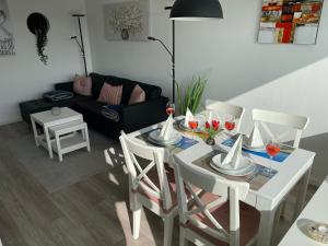 ein Wohnzimmer mit einem weißen Tisch und Stühlen in der Unterkunft Ferienpark - Haus O, App 0O0501 in Heiligenhafen