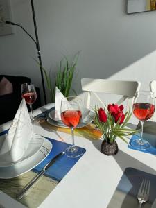 einen Tisch mit drei Gläsern Wein und roten Rosen in der Unterkunft Ferienpark - Haus O, App 0O0501 in Heiligenhafen