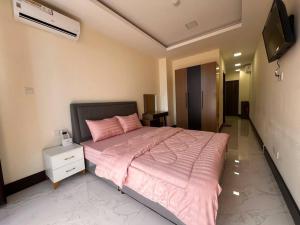 a bedroom with a bed with pink sheets and a tv at Ideal Budget and Cozy Private Studio with Amazing Pool by SYM C738 in Phnom Penh