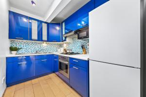una cocina azul con encimeras blancas y armarios azules en Balcony Blue Theme 1 Bedroom Central London Luxury Flat Near Hyde Park! Accommodates up to 6! Double Sofa Bed and Next to Station!, en Londres