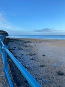 een blauw hek op een strand naast de oceaan bij Ger-Y-Bwlch - Spacious static on 5star site with Swimming Pool in Benllech